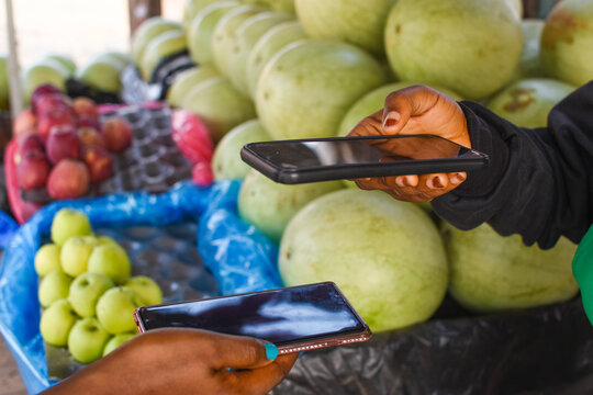 Two Hands Holding Smart Phones To Make Digital Payment For Transactions In A Market Place
