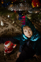 little boy in a dinosaur costume next to the Christmas tree, new year's eve