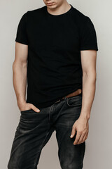 Obraz premium brutal attractive man poses in a black empty T-shirt made of thin premium cotton, highlighted on a white mock-up