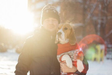 Man holding a dog dressed in a red knitted sweater on winter background
