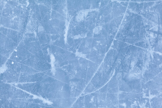 Empty ice rink with skate marks after the session outdoor. skating ice rink texture covered with snow in daylight. Close up of blue ice rink floor, copy space