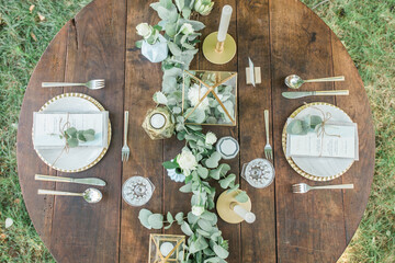 Bohemian wedding wooden table from above, eucalyptus and gold decoration.