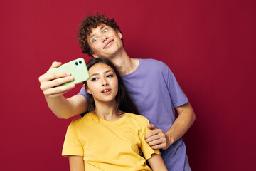 Naklejka premium Man and woman in colorful T-shirts with a phone isolated background