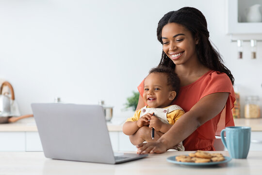 Freelance And Motherhood. Black Woman Holding Baby And Working On Laptop Computer