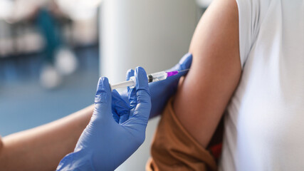 Young Woman Receiving Vaccine Injection Sitting With Doctor Indoor