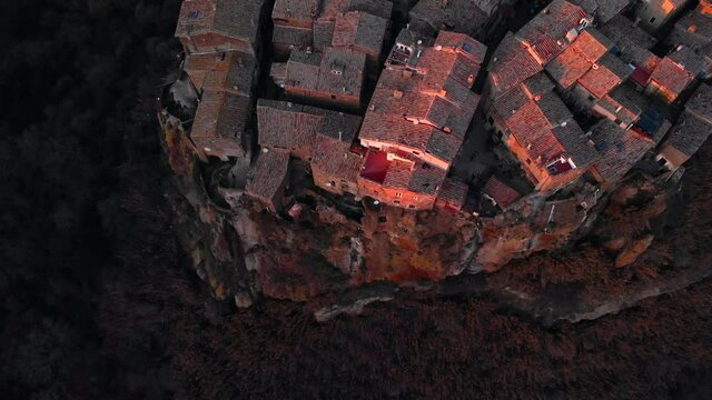 Beautiful on a gaint rock builded medieval Italian village Calcatai in light of a red colored sunset. Aerial tilt dolly drone shot.