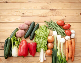 Close-up of group of assorted colorful fresh raw organic vegetables on a wooden table. Vegan, vegetarian detox diet, healthy eating, pepper, onion, cucumber, carrots, potatoes, tomatoes, zucchini