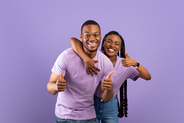 Happy black couple gesturing thumbs up and smiling