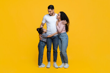 Happy Middle Eastern Family Of Three Standing Isolated Over Yellow Background