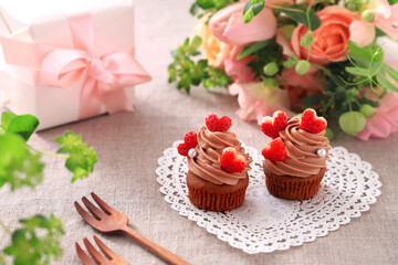 Obraz na płótnie Canvas Chocolate cupcakes with chocolate cream with strawberry heart. Valentine bouquet of rose flowers and gift.