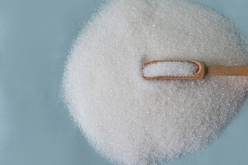 Close-up of granulated sugar in spoon and sugar pile