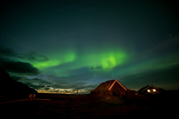 tourist camp with traditional houses under the starry sky with northern lights. Night photo. Iceland.