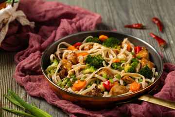 stir-fry pasta with chicken, broccoli and carrots.