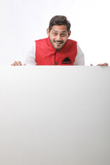 Indian man holding white board, promoting offers on festival season while wearing traditional cloths, standing over white background.