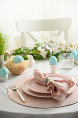 Easter table setting with blue coloful eggs, festive decorations, fresh flowers. Elegance dinner at home interior. Close up.