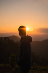 Fototapeta premium Traveler man standing on mountain peak in the sunset