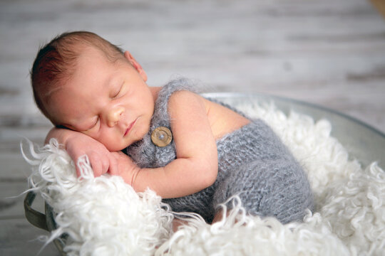 Newborn baby boy, sleeping peacefully in basket, dressed in knitted outfit,