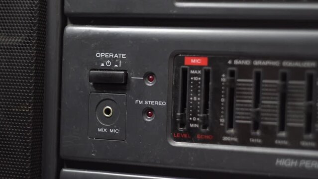 Turn off the power button on the cassette recorder. Dark body. Old tape recorder. Red LED. Close-up. Man's hand.