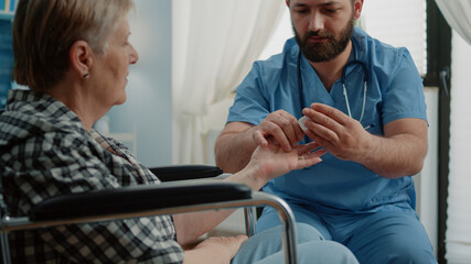 Senior woman in wheelchair getting medical visit at nursing home. Man nurse consulting retired...