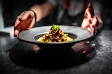 chef hand holding plate with Spelt with meat