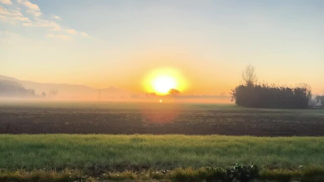 Beautiful winter sunrise in slow moton as seen from a moving car. Haze, meadows and sun.