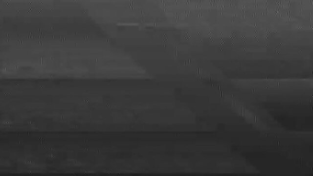 Glitch overlay. Distressed video. Old TV distortion. Black and white analog flicker noise on scratched grain texture screen dark background effect for transition.