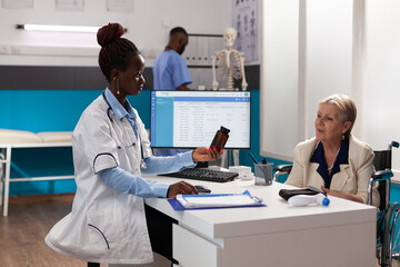 Therapist doctor holding pills bottle explaining disease diagnosis to senior invalid woman discussing medication treatment during medical appointment in hospital office. Concept of checkup visit