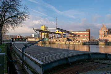 Obraz premium Inland cargo ship with old dock crane in the background. Malines, Belgium