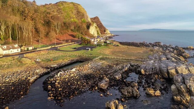 Atlantic coast with cliffs, Northern Ireland. Garron Point. Geological formation, parking and Causeway Coastal Route. One of the most scenic coastal roads in Europe. Aerial view. Sunrise light. Winter