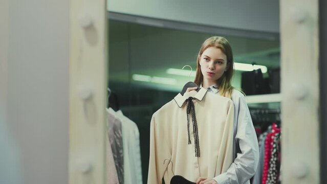 A pretty girl tries on clothes in the fitting room at a clothing store. Shopping