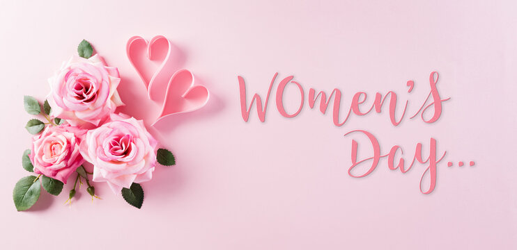 Happy Women's Day concept. Top view of roses flowers, heart and "Women's Day" text on pink pastel background.