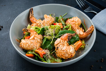 Shrimp salad with fresh green arugula leaves and avocado, almond and sesame seeds