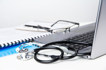 Doctor's workplace, laptop, stethoscope and documents on white table