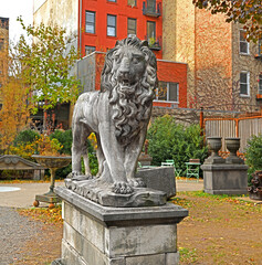 Antique sculpture of formidable and majestic lion in old autumn park. New York City