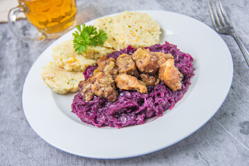 Roast pork with dumplings and sauerkraut. Typical Czech national dish with homemade bread dumplings red cabbage and beer on concrete background