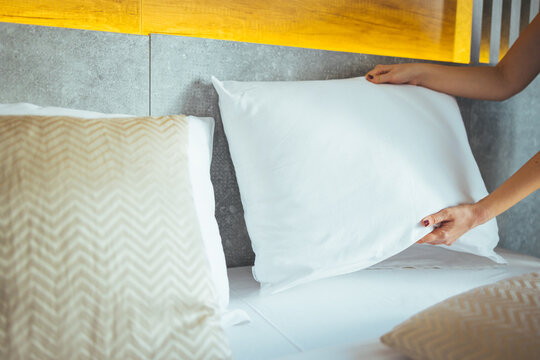 Maid making bed in hotel room. Female hands corrected pillow on the bed. Concept on preparation of bed in a hotel room or at home. Maid Making Bed