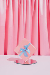 Romantic pastel pink composition with birthday or Valentine's Day gift box with mirror and satin background. Modern minimal concept.