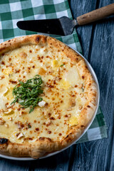 Tasty sliced pizza with fresh arugula and different kinds of cheese. Four cheese pizza, pizza Margarita.