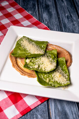 Hot ravioli with spinach served in a white plate with sause. Traditional italian cuisine, over rustic wooden table.