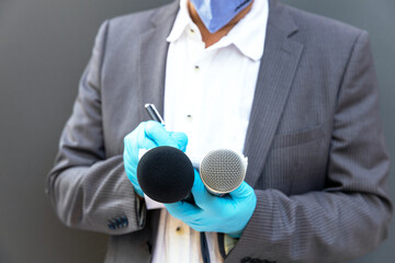 News reporter wearing protective gloves and face mask against coronavirus COVID-19 disease holding...