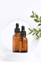 Amber glass dropper bottles different sizes on round form on white background with leaves. Cosmetic container mock-ups. Background for branding and packaging presentation. Natural skincare beauty