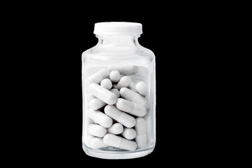 isolated on a black background glass jar with pills.