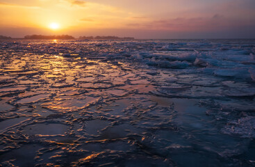 Fototapeta na wymiar Sunrise and frozen sea coast. Beautiful winter landscape with lake in morning time.