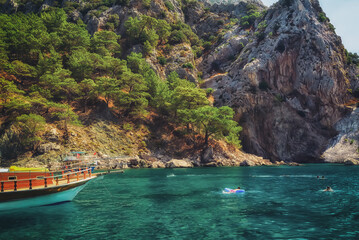 A beautiful bay at sea with a tourist ship and green cliffs on the shore. Turkey.
