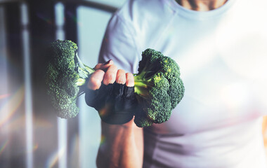 Fototapeta na wymiar Woman in the gym lifts a broccoli in the form of a dumbbell