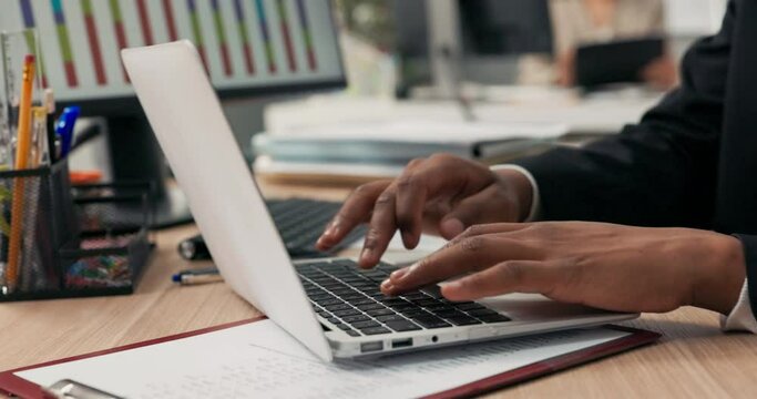 Close-up of silver latop standing on wooden desk, dark-skinned man working on it, young hands, typing text into keyboard, tapping fingers on computer