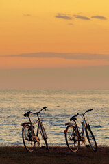 Fototapeta premium Silhouette of two bicycles by the sea after sunset