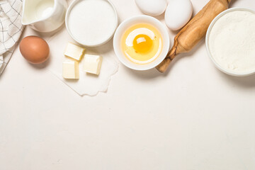 Ingredients for baking at white table. Flour, sugar, eggs and utensils. Top view with copy space.