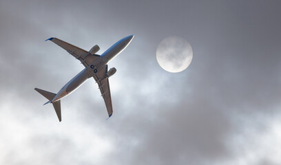 A white passenger plane fly in the sky with the sun shining through the clouds in the background