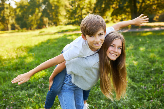 Schwester tr&auml;gt ihren Bruder Huckepack im Park